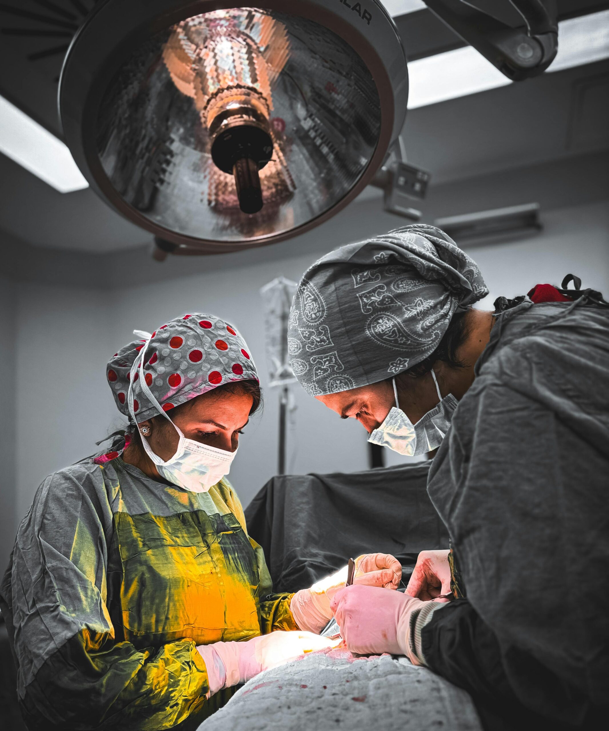 Two surgeons focus on a procedure under bright surgical lights, showcasing teamwork in healthcare.